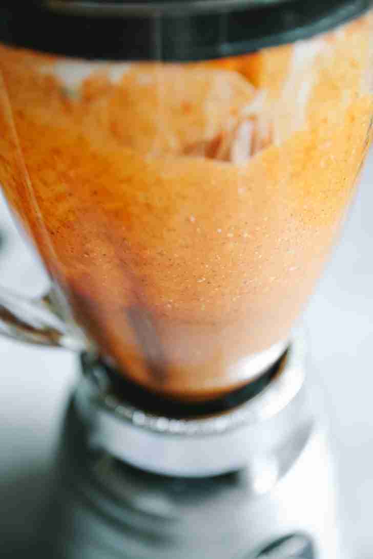 The Blue Heat Wing Sauce blending into a smooth, orange mixture in a blender, combining spicy and creamy ingredients.