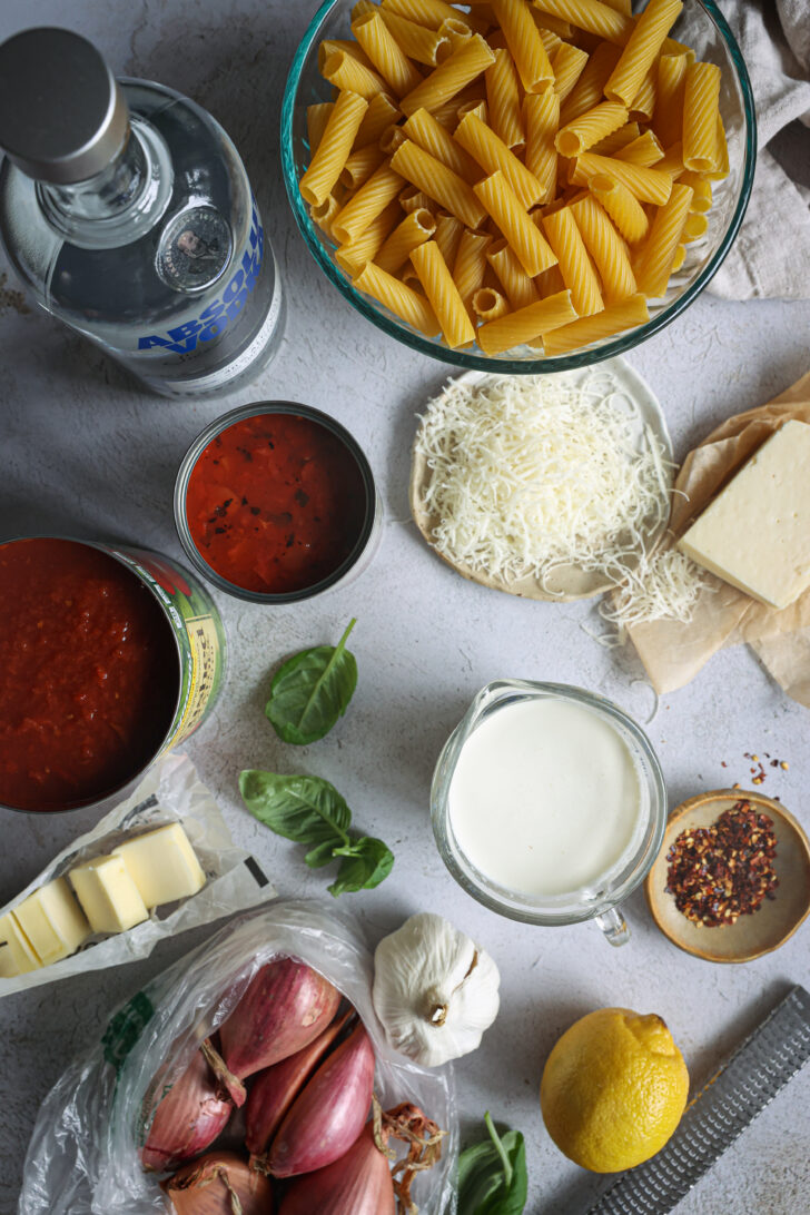 Ingredients for vodka sauce pasta, including rigatoni, vodka, tomatoes, cream, Parmesan, butter, shallots, garlic, and basil.