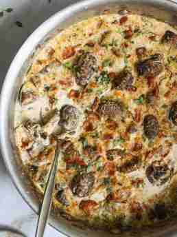 Golden, cheesy mushroom and bacon gratin in a skillet, topped with fresh herbs and a bubbly crust. Rich and creamy, ready to serve.