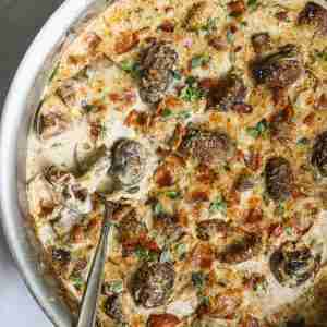 Golden, cheesy mushroom and bacon gratin in a skillet, topped with fresh herbs and a bubbly crust. Rich and creamy, ready to serve.