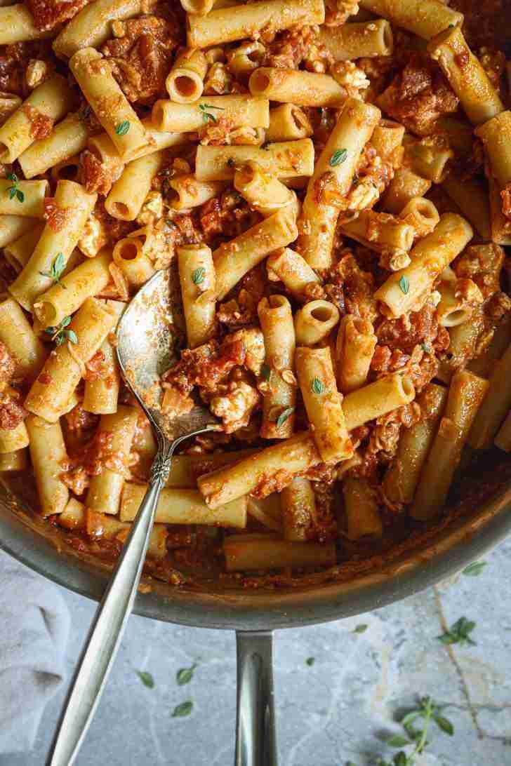 Cooked ziti pasta tossed in a rich tomato and blue cheese sauce, garnished with fresh herbs. A serving spoon is nestled among the pasta, ready to serve, with the creamy sauce clinging to the ziti for a hearty, flavorful dish