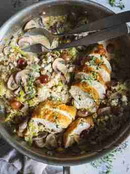 Golden roast chicken sliced in a skillet, served with a creamy leek, mushroom, and grape mixture over a bed of harvest rice.