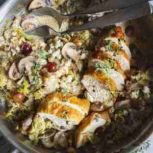 Golden roast chicken sliced in a skillet, served with a creamy leek, mushroom, and grape mixture over a bed of harvest rice.