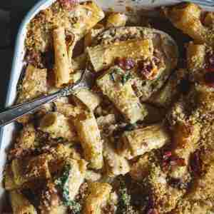 Baked mac and cheese with rigatoni, crispy breadcrumbs, and bacon, topped with a golden crust in a white baking dish, ready to serve.