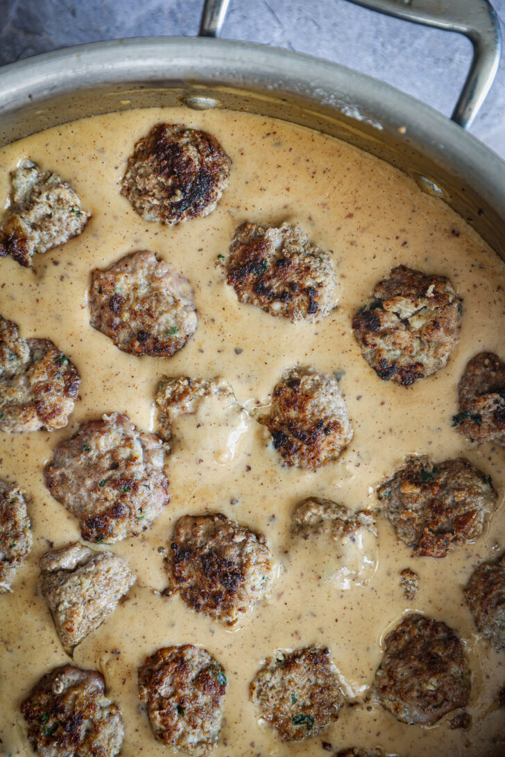 Cooked Swedish meatballs simmering in creamy gravy, with golden-brown crusts soaking up the flavorful sauce.