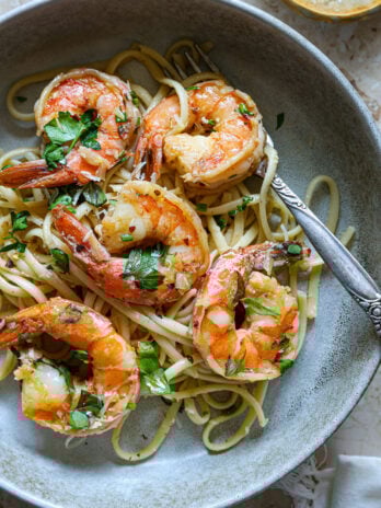 Plated shrimp scampi with linguine, fresh herbs, and a vintage fork in a stoneware bowl—saucy, vibrant, and ready to eat.